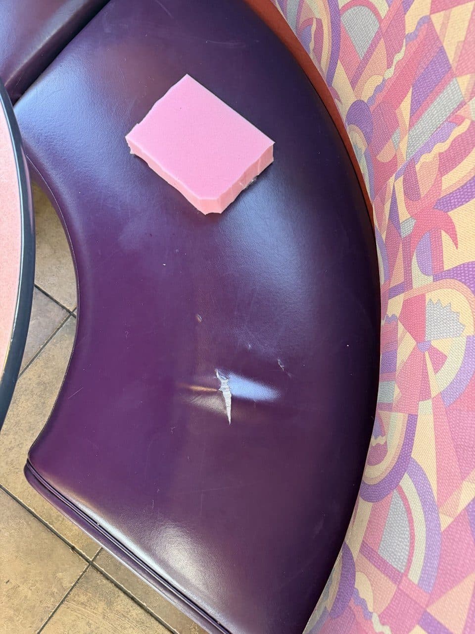 Curved end of a restaurant booth with a clean cut through the vinyl