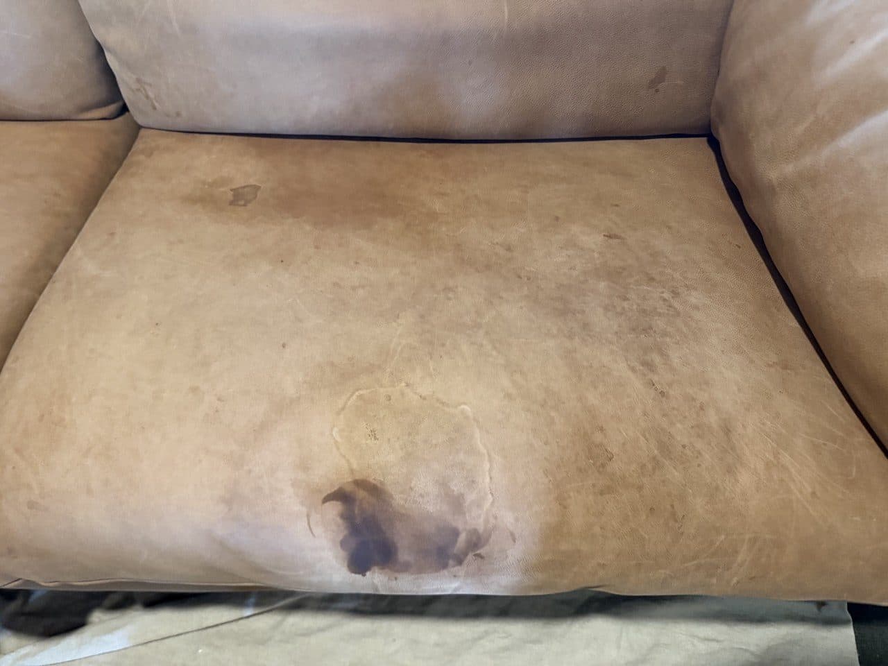 Before: Oil stain spread across a full-grain aniline couch seat